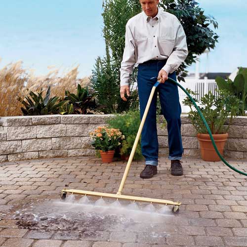 ways to save water outside the home - man using water broom pressure washer to clean off patio