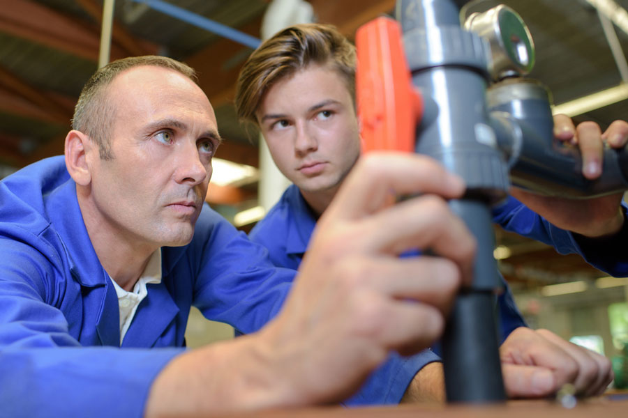 Plumbing apprenticeship - mentor teaching student hands-on about plumbingl