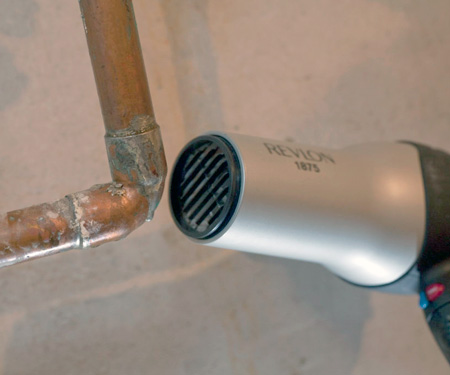 how to thaw frozen pipes - blowing warm air on frozen copper pipe with a hair dryer
