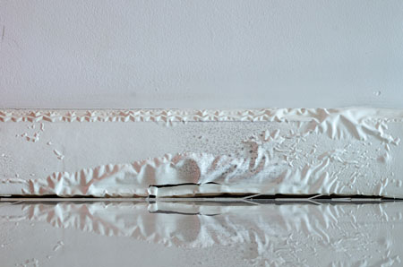 water damage on baseboards - paint peeling and bubbling
