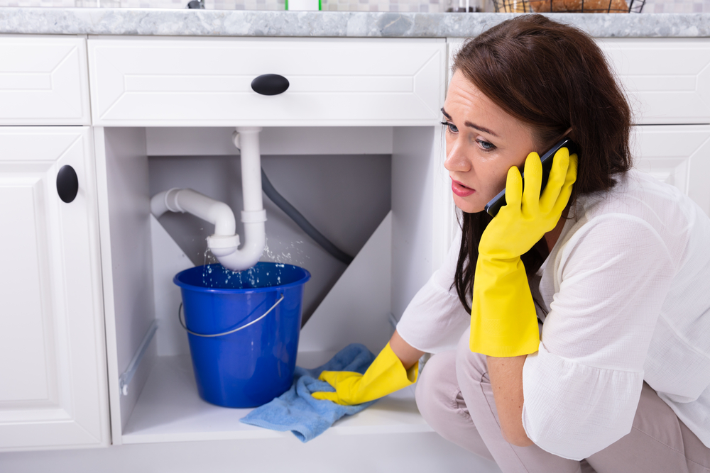 what to do in a plumbing emergency - woman with leak calling plumber