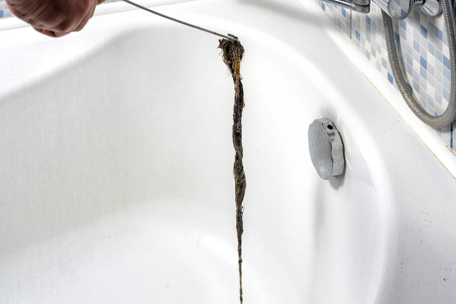 A plumber's snake or wire hanger is a great way to retrieve hair out of your drain and clear that clog.