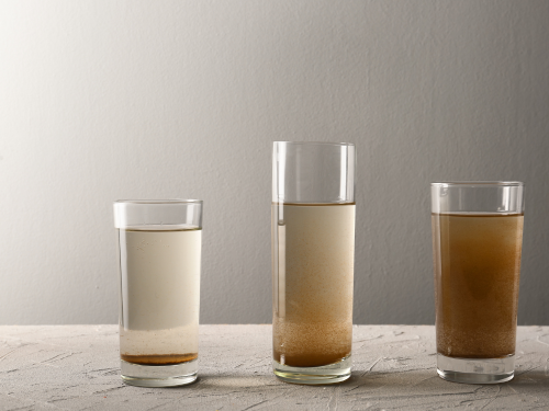 Three glasses filled with brown water. 